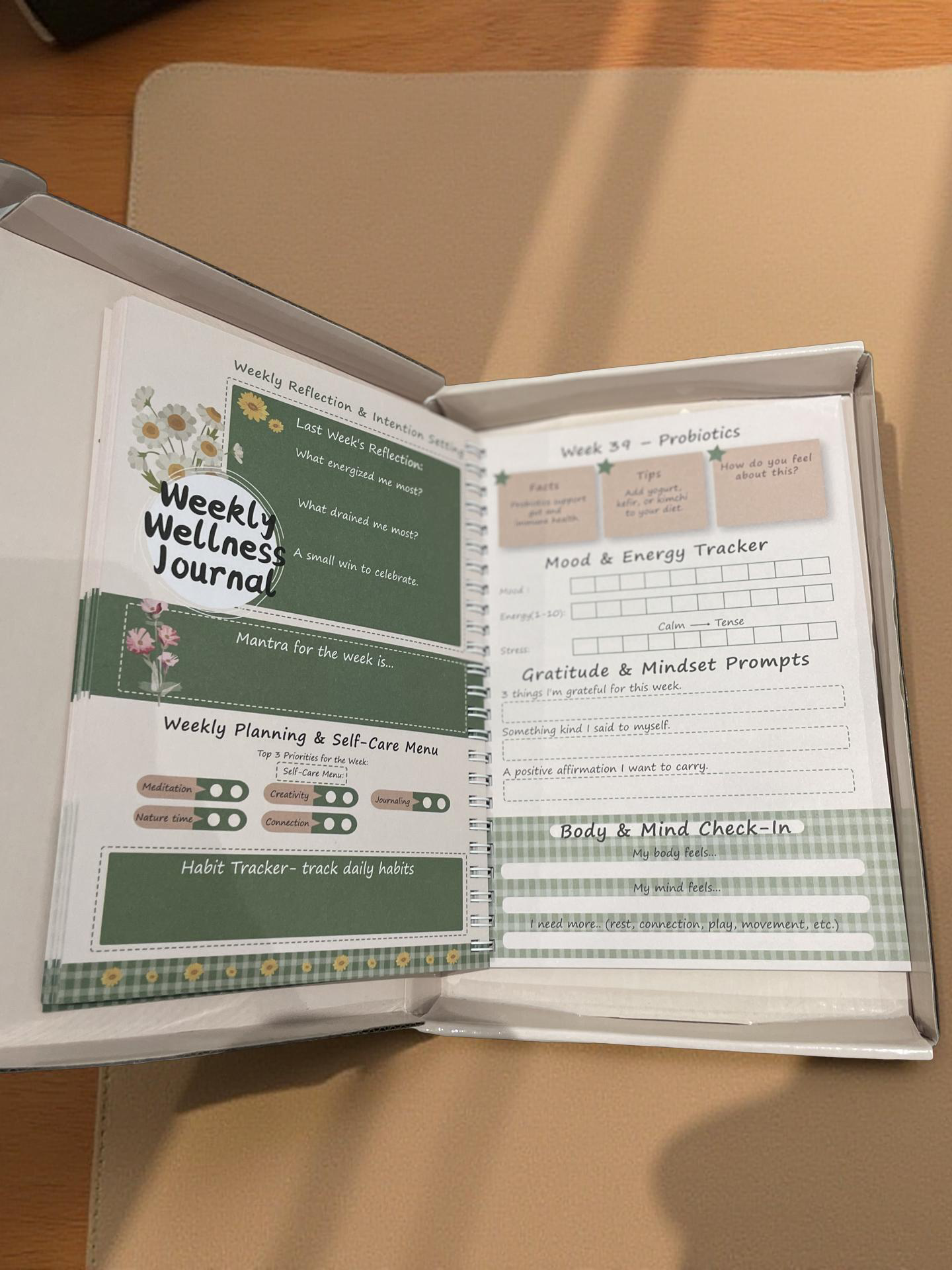 Open essential oil infused journal by Tolicious Brand featuring weekly wellness prompts and habit trackers